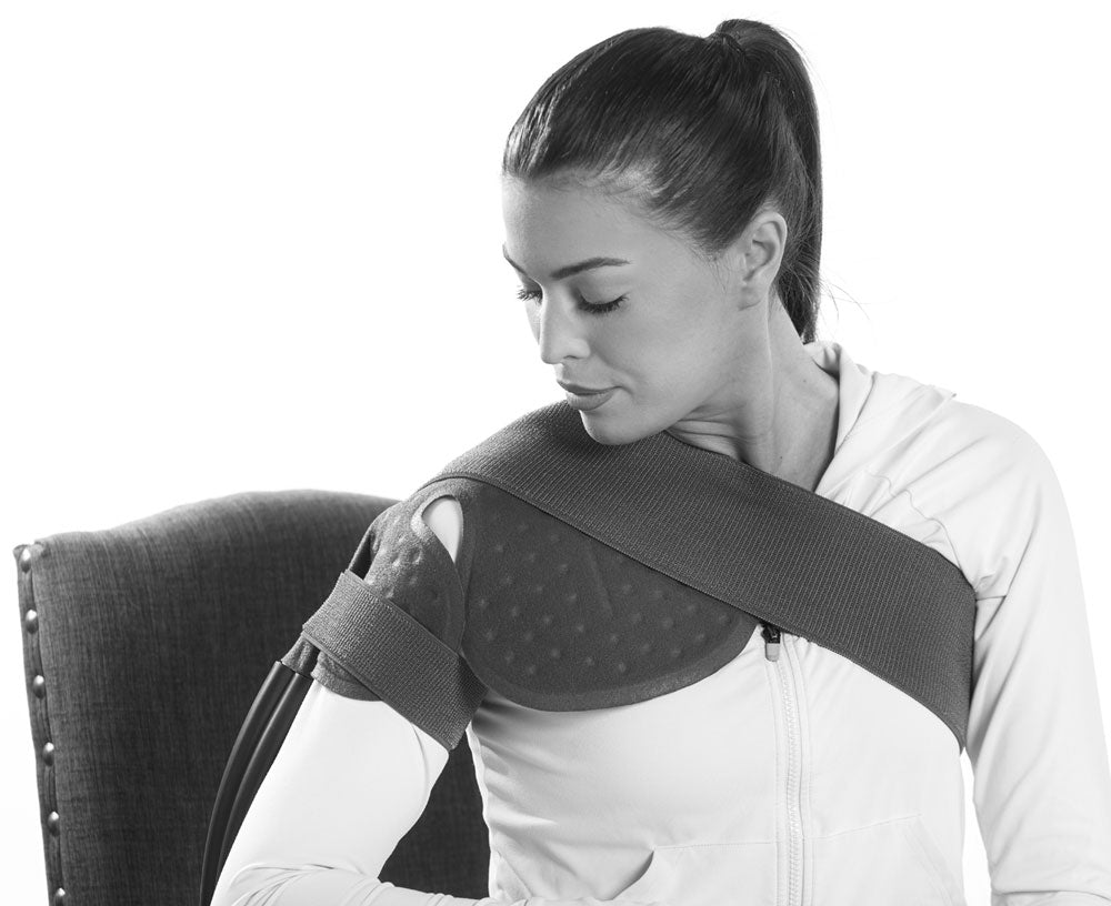 A woman seated and wearing a shoulder cooling pad.